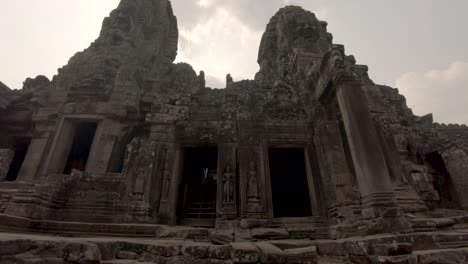 historical building facade of bayon temple within angkor complex, cambodia, tilting upward shot