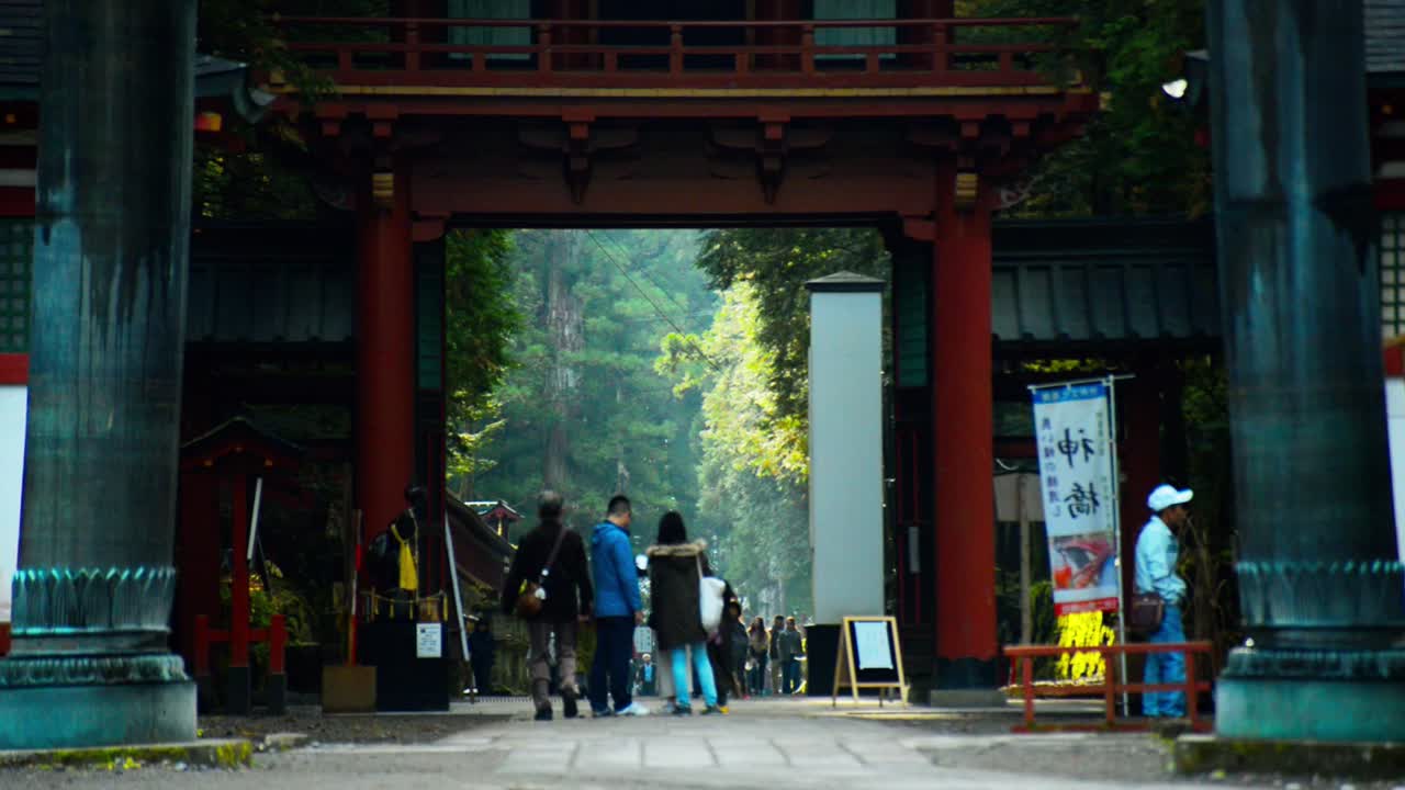 People walking through a japanese torii, gate. Temple district of Nikko, Japan