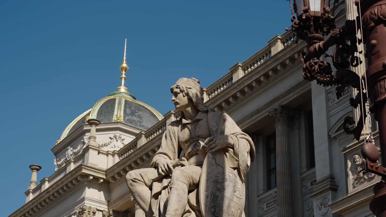 Statue with detailed robe sits before the golden dome of Prague’s National Museum