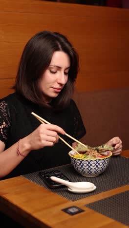 una mujer comiendo ramen.