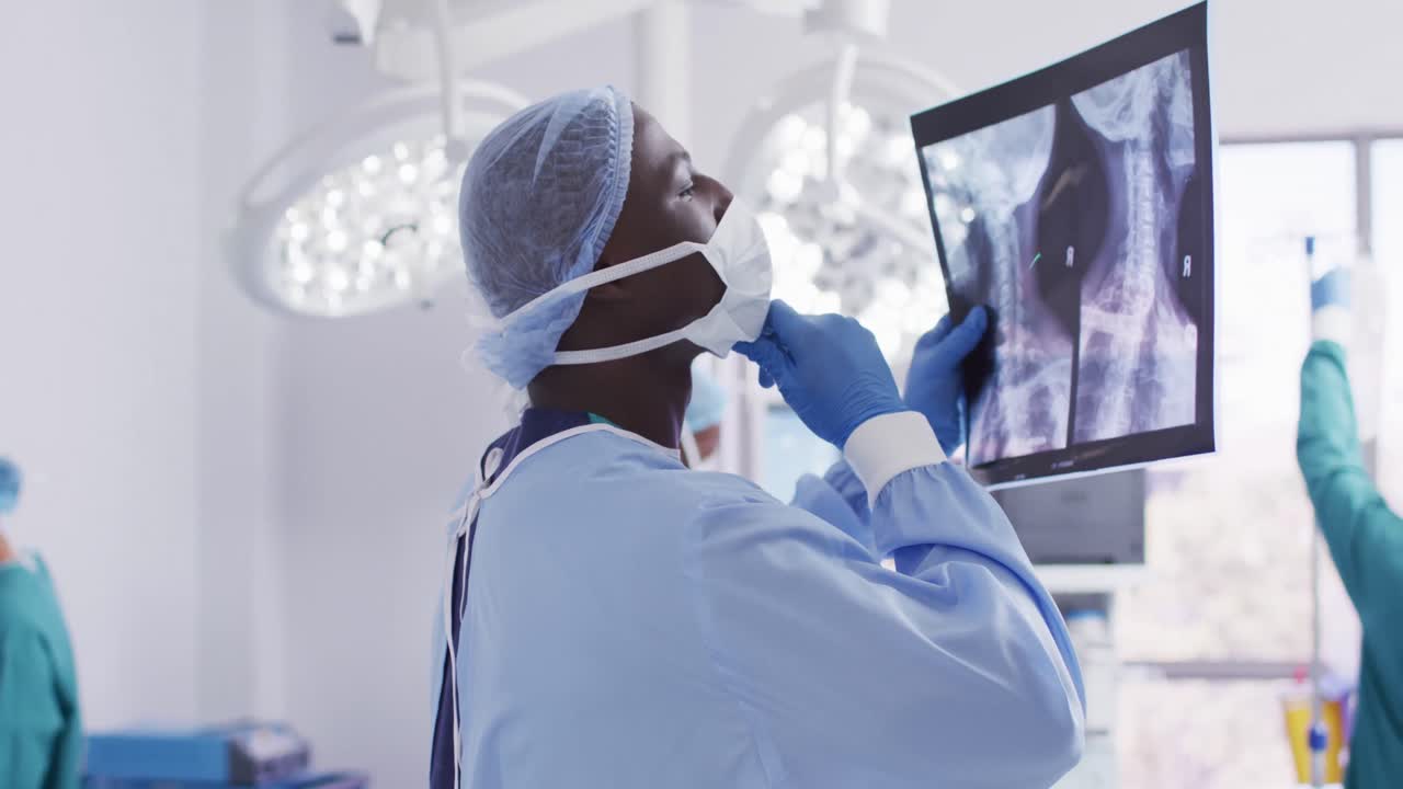 Video of african american male surgeon studying x-ray in operating theatre