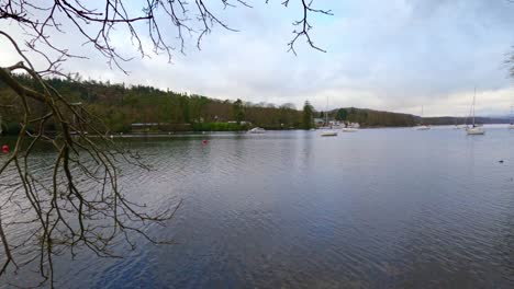 lake windermere in the english lake district, with its iconic wooden jetty, historic stone-built buildings, and moody grey skies