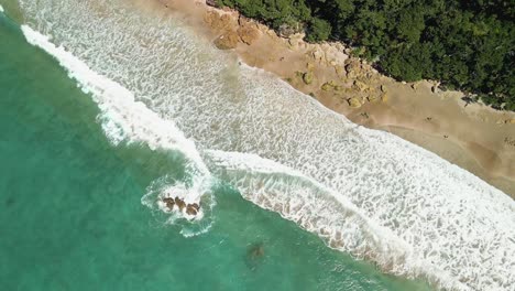 Drone-hovering-over-Hot-Water-Beach-hot-spring-along-coast-line-of-the-Coromandel-Peninsula-in-New-Zealand