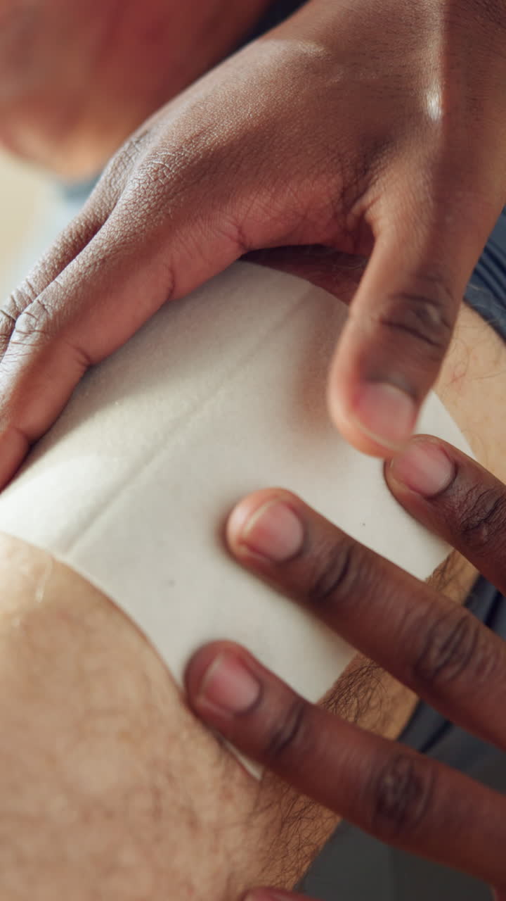 Nahaufnahme von Händen, die einen Wachsstreifen auf ein behaartes Bein auftragen