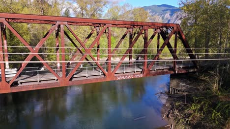 scenic ascending shot of bridge from snoqualmie middle fork river with mountains in the background in north bend, washington state