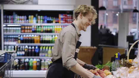 happy worker in a black apron is holding a crate of apples. work in the store. weekdays. healthy food