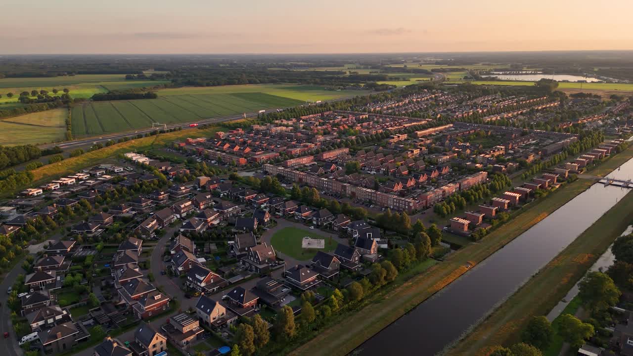 Aerial View of a Residential Neighborhood with Canal and Green Fields at Sunset