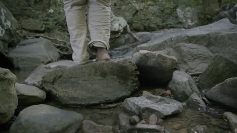 bare feet of a teenager walking on rocks in a stream