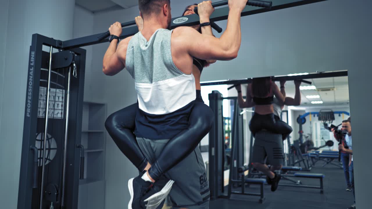 Young couple is working out at gym. Attractive woman and handsome muscular man are training in light modern gym