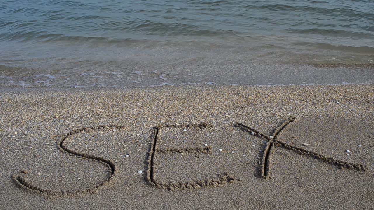 sex handwritten in sand on a beach. Shooting on the beach