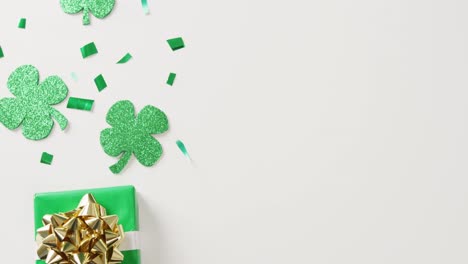 Video-of-st-patrick's-shamrock-leaves-and-present-with-copy-space-on-white-background