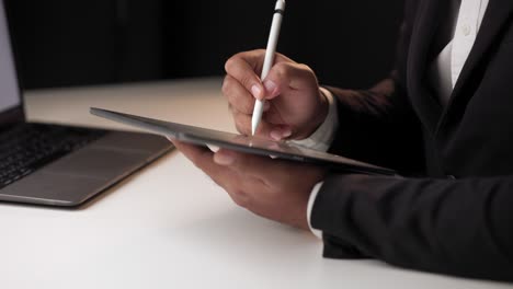 businessman signing a business contract with stylus pen on tablet at night. man signing contract on tablet at office. business and technology concept. electronic signature concept