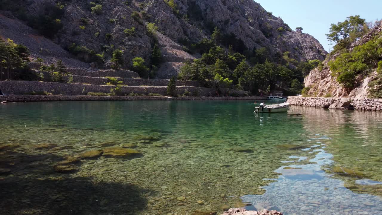 A mesmerizing drone perspective captures anchored boats, tourists, and the magnificent Croatian Mediterranean shoreline bathed in the warmth of a summer's day at Zavratnica Inlet