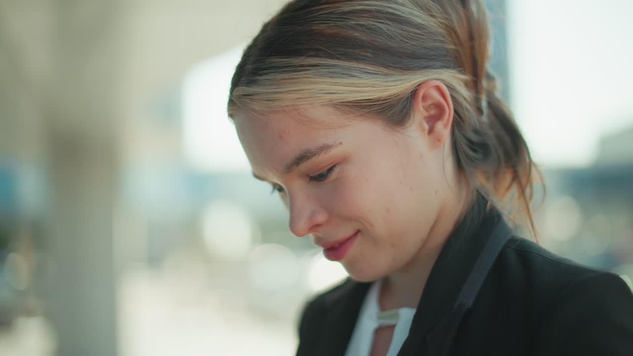 Close-up of elegant lady with cat eyes, smiling and staring at the camera, wearing suit in professional attire, with blurred urban background