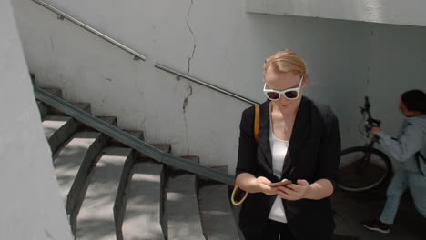 woman using smartphone on city stairs