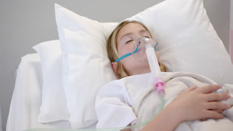 caucasian girl patient in oxygen mask asleep in hospital bed, copy space, slow motion