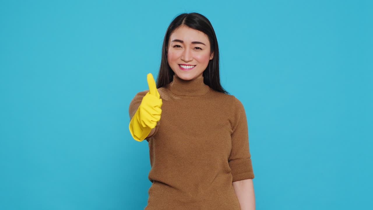 Joyful maid posing in studio doing approve gesture in front of camera after finishing cleaning