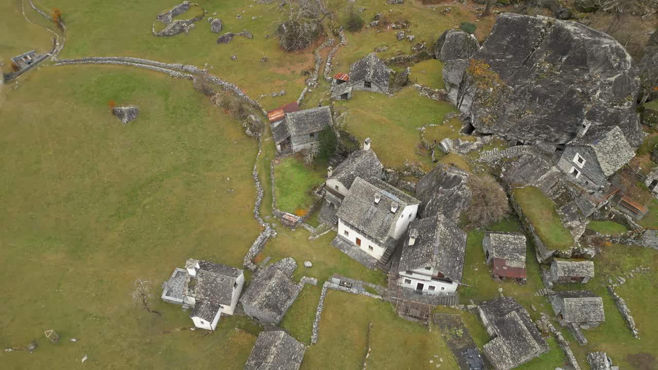 Aerial drone bird's eye view flying high over old stonewalled village houses in Cavergno, District of Vallemaggia, Canton of Ticino in Switzerland at daytime