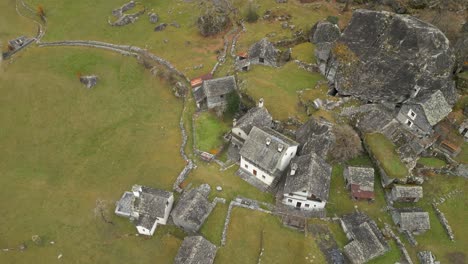 Vista-Aérea-De-Drones-Volando-Alto-Sobre-Antiguas-Casas-De-Pueblo-Con-Paredes-De-Piedra-En-Cavergno,-Distrito-De-Vallemaggia,-Cantón-De-Ticino-En-Suiza-Durante-El-Día