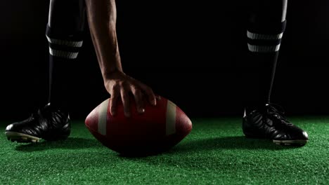 american football player bending holding a ball on turf with his hands 4k