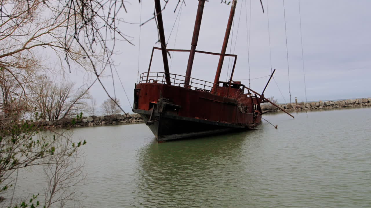 Rusty red shipwreck stuck in shallow green water