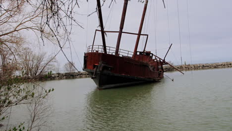 rusty red shipwreck stuck in shallow green water