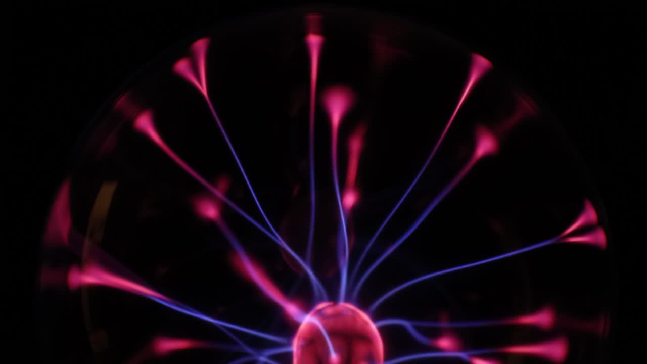 A stunning plasma globe radiates vibrant blue and pink electric arcs from its core, creating a mesmerizing and colorful display of static energy in the dark