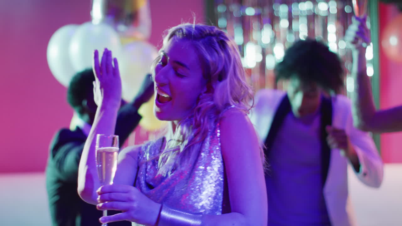 Video of happy caucasian woman dancing holding a glass of champagne at a nightclub