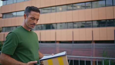 delivery guy carrying parcel stepping street closeup. man checking smartphone