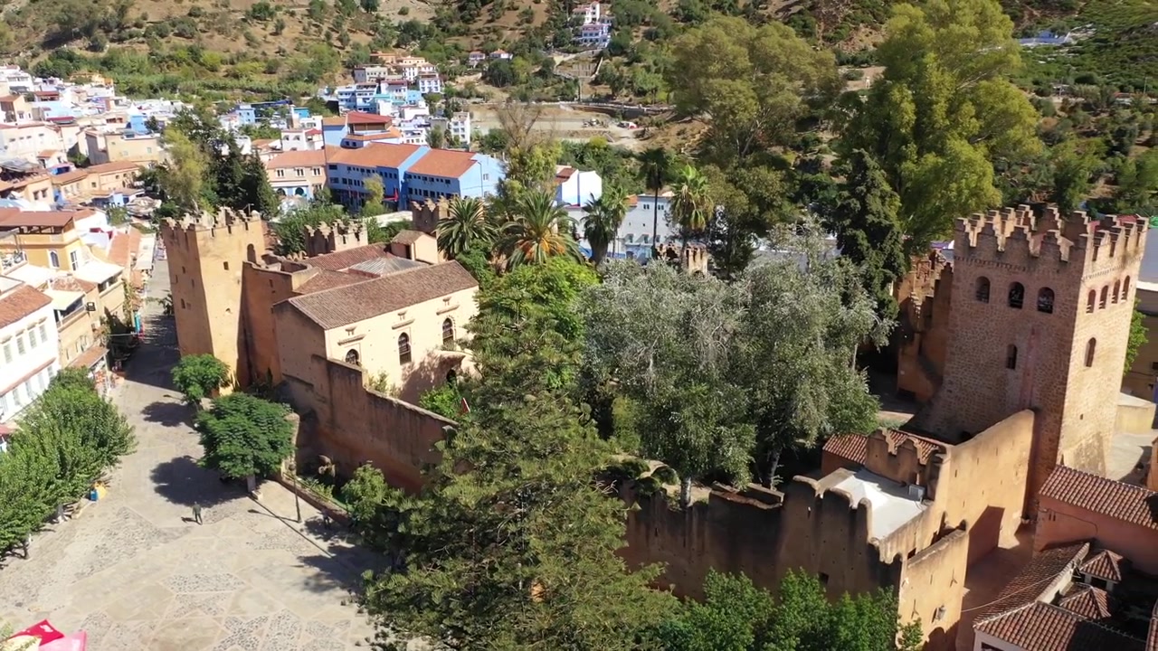 Widok z drona na historyczną Kasbę Chefchaouen, z której roztacza się widok na Plac Outa el Hammam, prezentującą jeden z najbardziej ikonicznych zabytków kultury Maroka w sercu słynnego Błękitnego Miasta.
