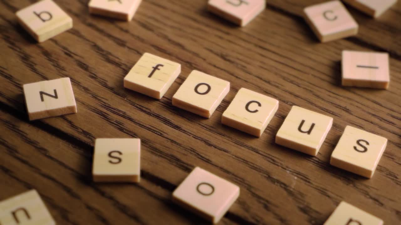 Wooden tiles spell the word focus as the camera pans steadily across a rustic wooden surface.