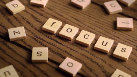 wooden tiles spell the word focus as the camera pans steadily across a rustic wooden surface.