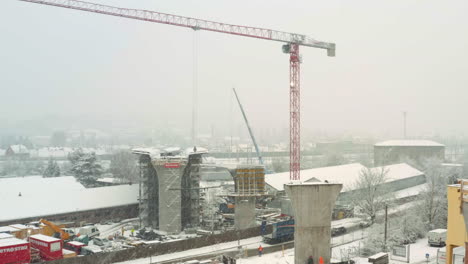 Grúa-Torre-Moviéndose-En-Una-Tormenta-De-Nieve-En-El-Sitio-De-Construcción-Del-Puente-De-La-Carretera