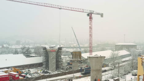 grúa torre que se mueve en una tormenta de nieve en el sitio de construcción del puente de la autopista