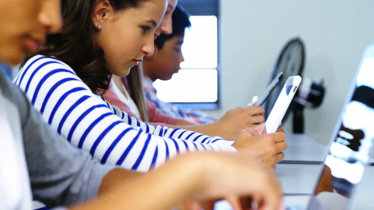 estudiantes que usan tabletas digitales y computadoras portátiles en el aula
