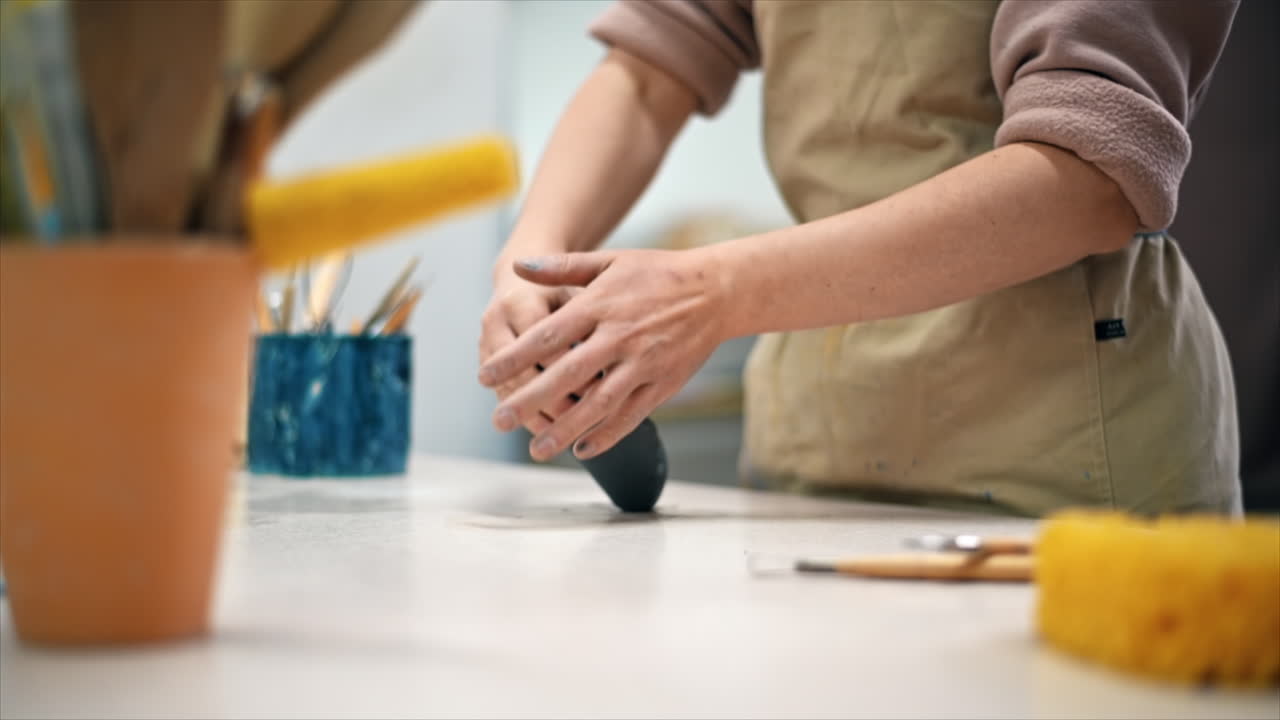 The master of sculpting pottery working in a studio. Kneading a piece of clay with her hands. Tools on the table. Slow motion