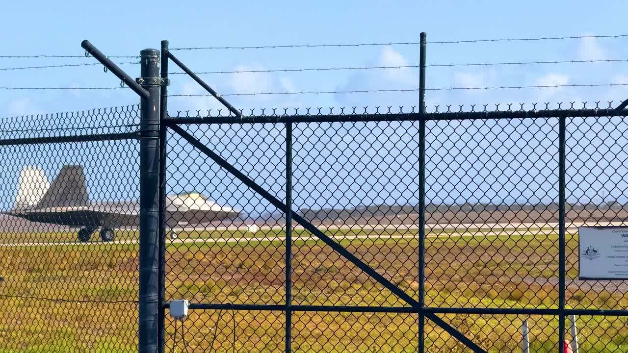 An F-22 Raptor taxis on a runway behind a fence at Avalon Airshow, Geelong, under clear skies