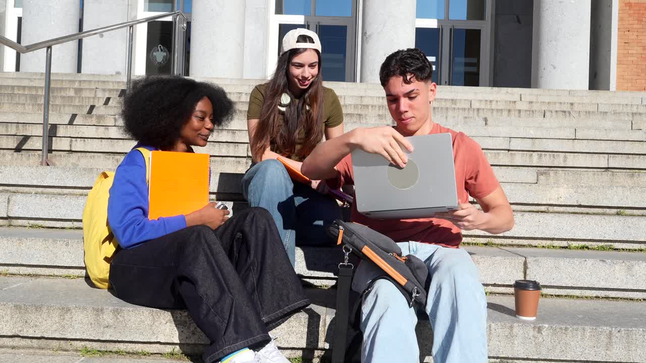 Mangfoldig gruppe studenter diskuterer ved en bærbar PC utendørs på campusens trapper