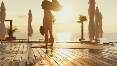 the guy took a pose during a yoga class. he stands on his hands, holding his body above theirs. yoga and meditation session on a sunny beach in the morning