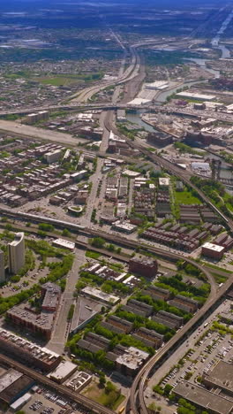 extensive city scenery lined with numerous roads. drone flying high over the metropolis on sunny day. chicago, illinois, usa. vertical video