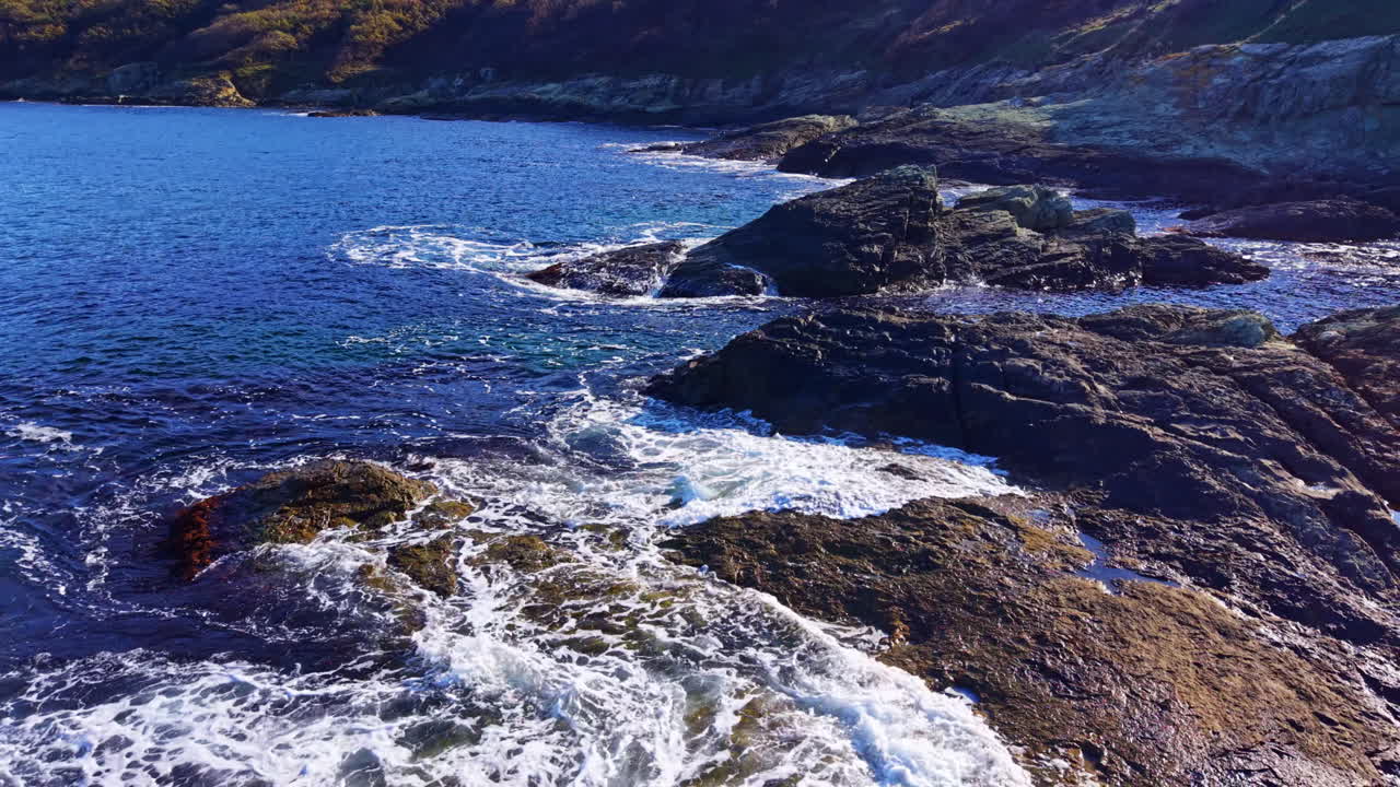 Soothing ocean waves caress rugged rocks along a serene coastline at sunset revealing nature's tranquil beauty