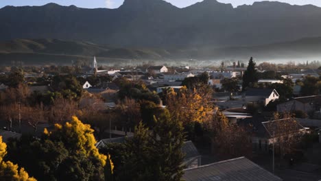 view over urban area in morning light with misty mountain range in background pan and upward tilt