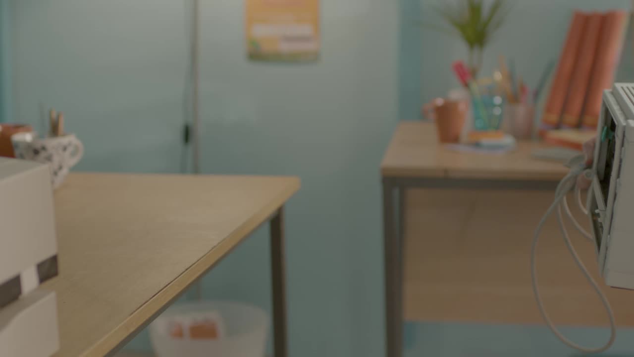 Person setting up or installing two beige printers on a wooden desk