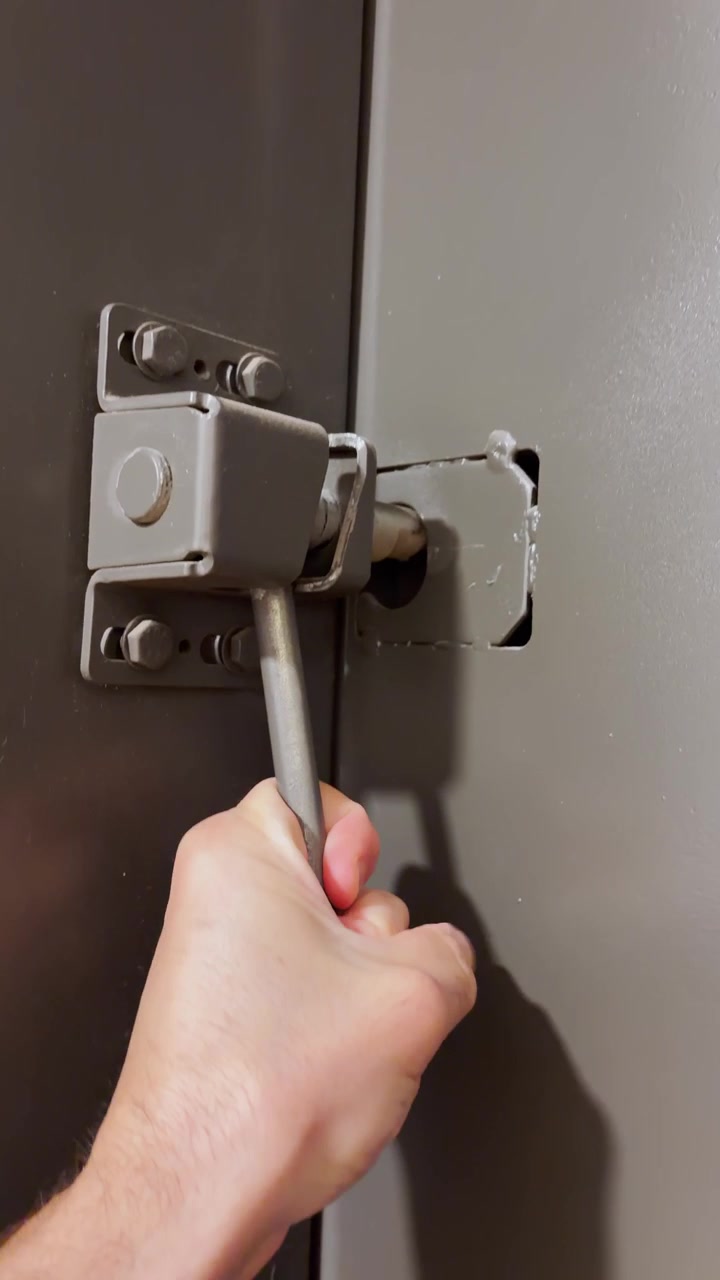 Mano en primera persona (POV) cerrando la puerta metálica de un refugio para asegurar contra ataques y protección. Vista estilo reel de redes sociales UGC de una mano masculina usando una barra de acero para cerrar de forma segura la puerta de una ventana para defensa contra ondas expansivas explosivas.