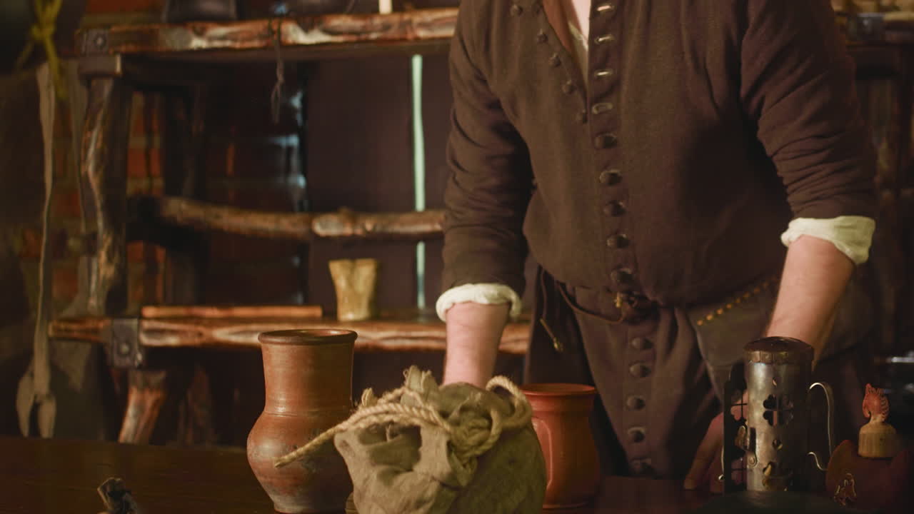 el posadero se encoge de hombros mientras el caballero bebe en la taberna de primer plano. el barman medieval sirve bebidas alcohólicas al guerrero viajero en la posada. el dueño del hotel con el invitado