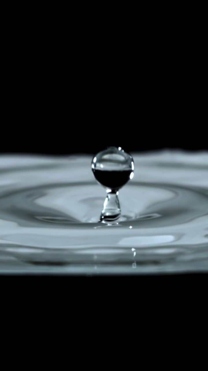 Slow Motion Water Drop Falling and Creating Ripples on a Liquid Surface