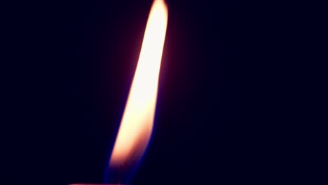 Single-big-yellow-candle-flame-lights-and-extinguish,-isolated-on-a-black-background