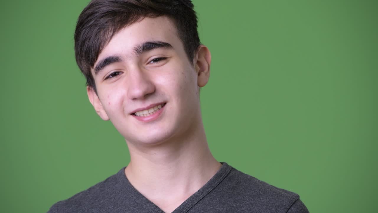 초록색 배경에 젊은 잘생긴 이란 십대 소년