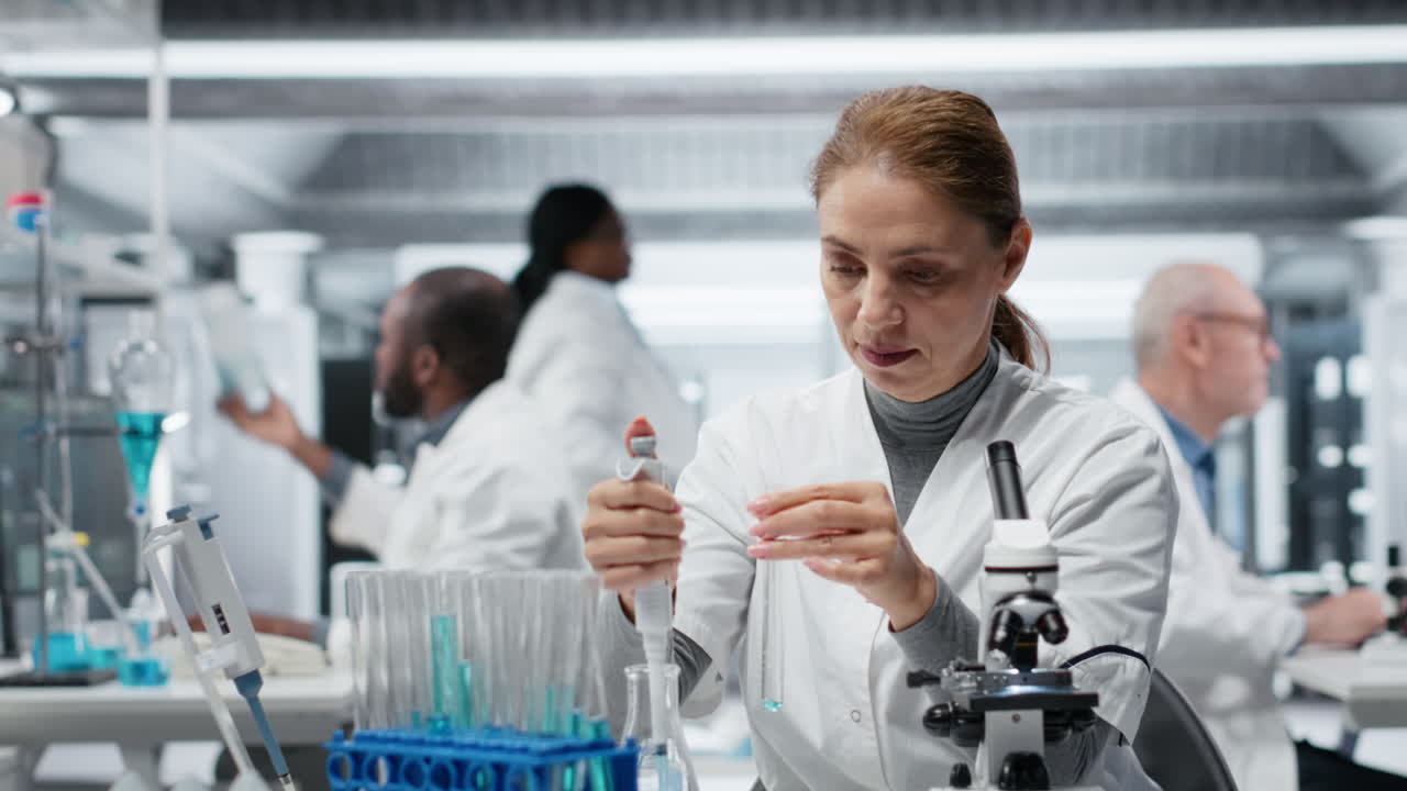 Assay development specialist in lab pipetting blue liquid into test tube