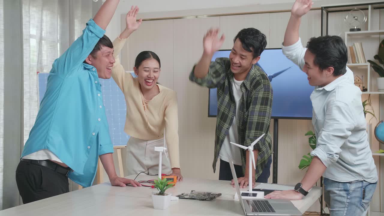 아시아 엔지니어 그룹이 사무실에서 풍력 터빈에 대해 작업하는 동안 함께 손을 고 있습니다.